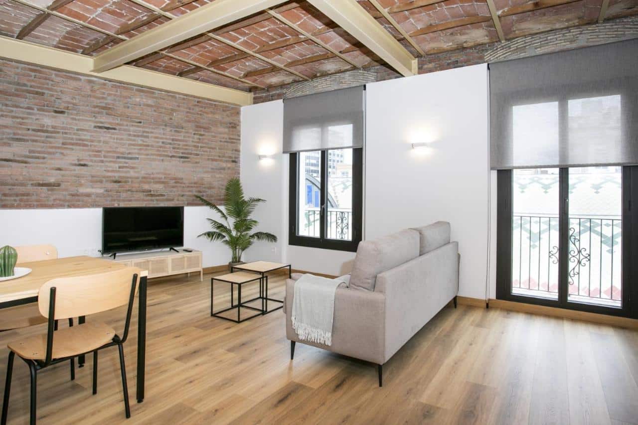 Apartament modern amb menjador, sofà, televisió, finestra i balcó amb vistes a la plaça Corsini i el Mercat Central de Tarragona, ideal per a estades curtes o llargues.