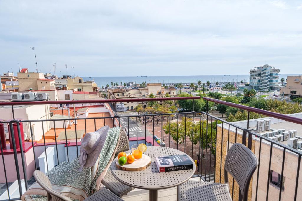 Apartaments Reial Foto del balcó de TGNA Reial 1, amb vistes a la plaça dels Carros, l'edifici de l'Autoritat Portuària de Tarragona i el Mar Mediterrani, amb una petita taula de lectura i 3 cadires per esmorzar, llegir o relaxar-se. Espai exterior tranquil per gaudir del temps lliure al centre de Tarragona.
