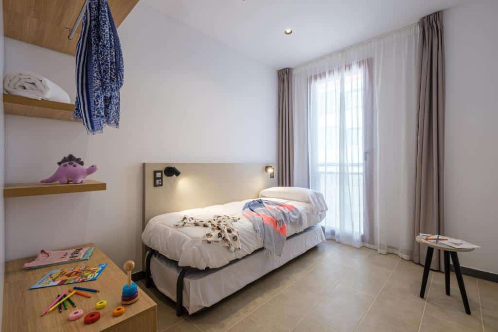 Foto d'una habitació infantil amb dos llits individuals en un apartament turístic a TGNA Reding 22, ideal per a famílies que visiten Tarragona. Espai lluminós i còmode per als més petits, amb tot el necessari per a una estada agradable.