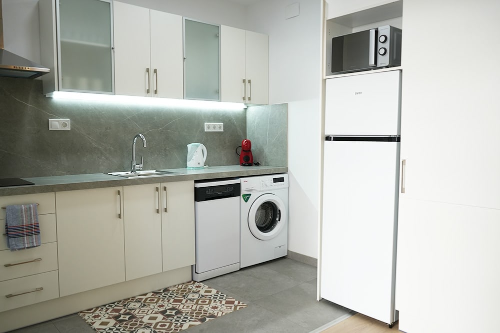 Cuina de TGNA Llúria 11, apartament turístic modern situat a Tarragona, capital de la Costa Daurada. La cuina, equipada amb electrodomèstics de qualitat, és perfecta per preparar àpats durant la seva estada. L'espai està dissenyat per a famílies, parelles i nòmades digitals que busquen allotjament còmode i pràctic en una ubicació privilegiada a prop de la Rambla Nova i les platges de Tarragona.