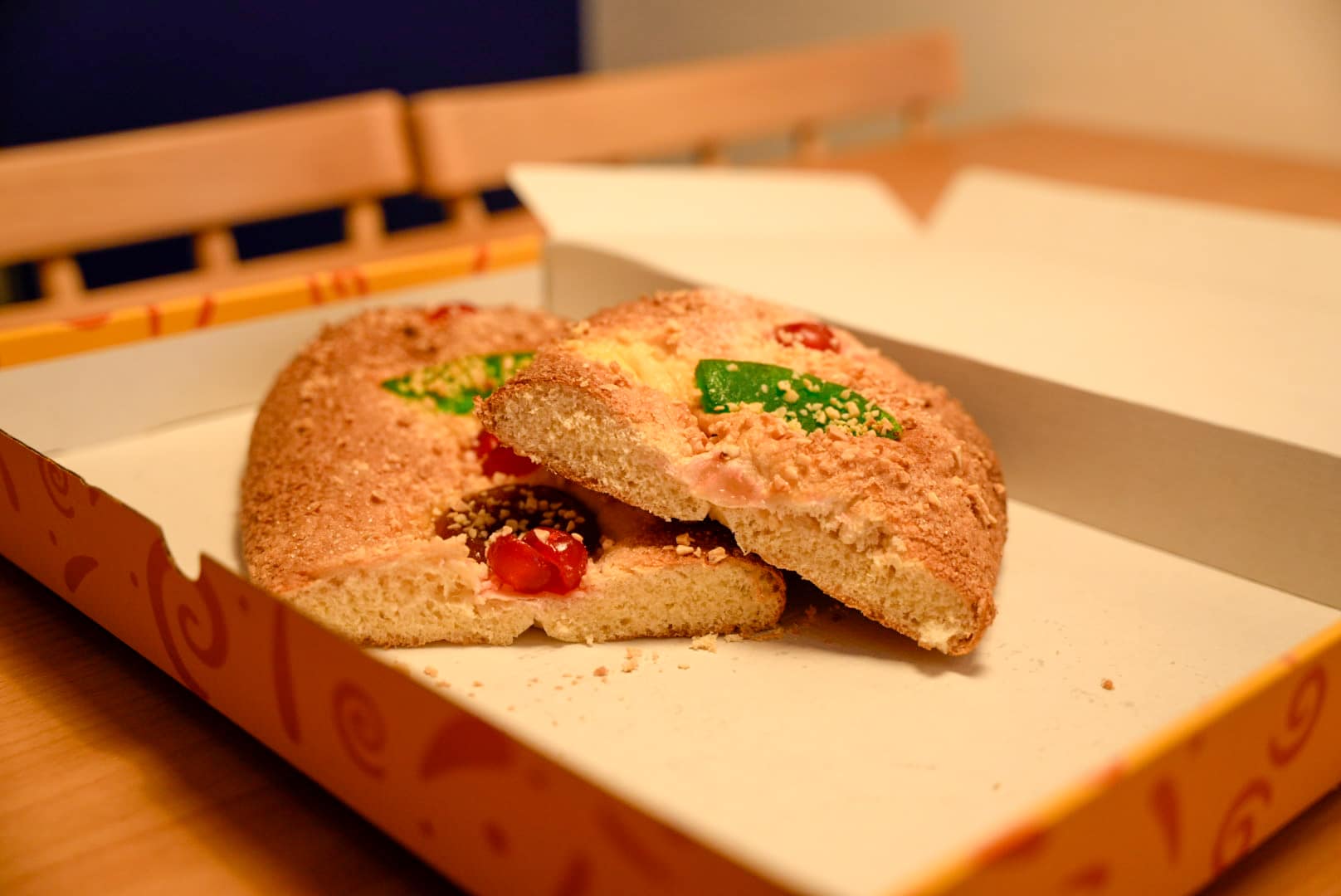 Dos talls de coca de Sant Joan de fruita tradicional servits en un plat sobre la taula de l'allotjament TGNA Cervantes 8, amb la caixa de fons.
